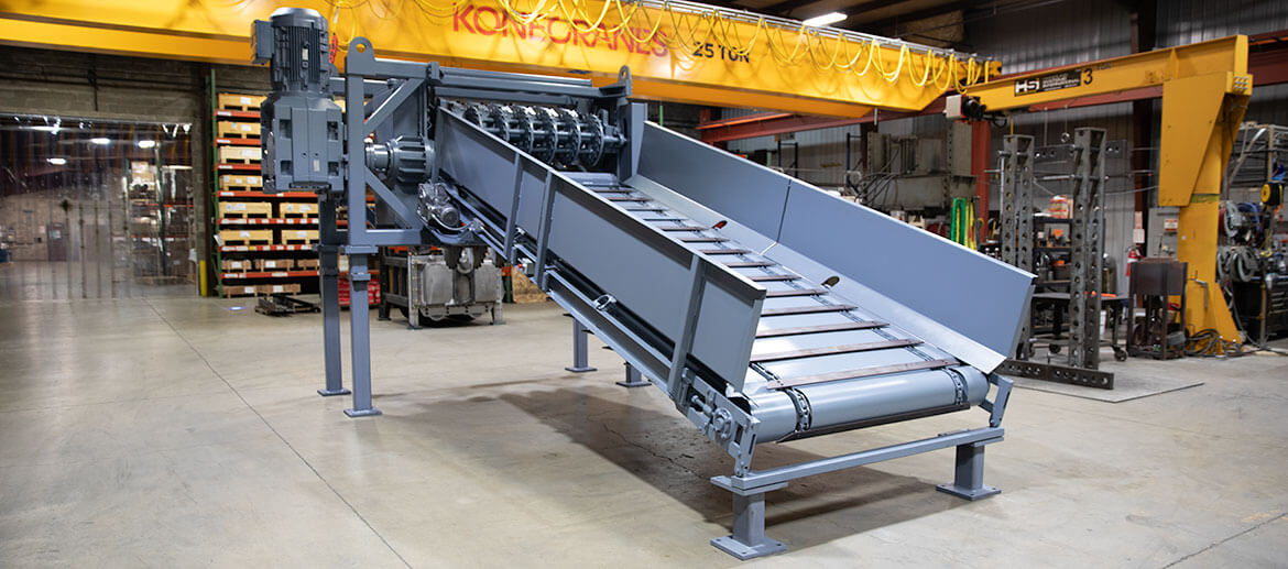 The primary tire shredder has a conveyor belt on it and is a light blue color.